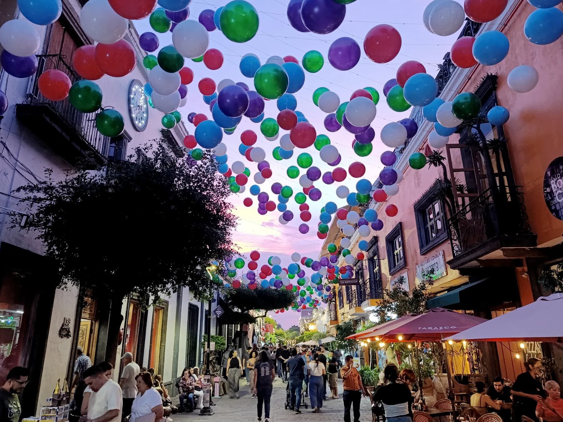 Calle del centro de Tlaquepaque al anochecer con globos de colores sobre el andador